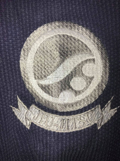Shoyoroll Batch #8: The Yank, a navy blue Jiu-Jitsu gi featuring a lightweight 450 GSM pearl weave jacket and 12 oz ripstop cotton pants, part of the East vs. West series inspired by baseball legend 'The Great Bambino.' Includes contrast stitching, a foam collar, stretchy drawstring, ID/iPod pocket, and custom inner taping.