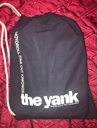 Shoyoroll Batch #8: The Yank, a navy blue Jiu-Jitsu gi featuring a lightweight 450 GSM pearl weave jacket and 12 oz ripstop cotton pants, part of the East vs. West series inspired by baseball legend 'The Great Bambino.' Includes contrast stitching, a foam collar, stretchy drawstring, ID/iPod pocket, and custom inner taping.
