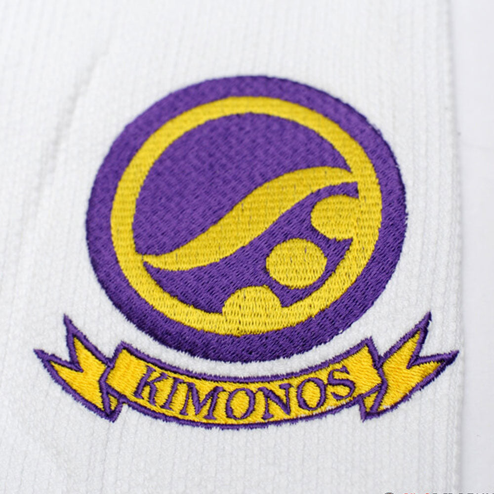 Shoyoroll Batch #8 White Mamba Gi, featuring a lightweight 450 GSM pearl weave jacket and 12 oz ripstop pants. Designed by artist John Smalls, this gi showcases a white base with purple trim. Released as part of the East vs. West Series on December 22, 2010, at 3:00 PM PST.
