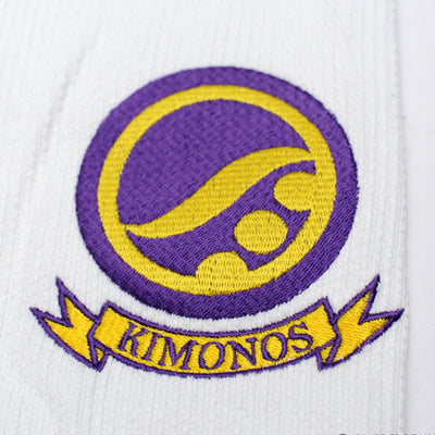 Shoyoroll Batch #8 White Mamba Gi, featuring a lightweight 450 GSM pearl weave jacket and 12 oz ripstop pants. Designed by artist John Smalls, this gi showcases a white base with purple trim. Released as part of the East vs. West Series on December 22, 2010, at 3:00 PM PST.