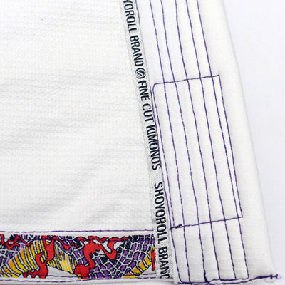 Shoyoroll Batch #8 White Mamba Gi, featuring a lightweight 450 GSM pearl weave jacket and 12 oz ripstop pants. Designed by artist John Smalls, this gi showcases a white base with purple trim. Released as part of the East vs. West Series on December 22, 2010, at 3:00 PM PST.
