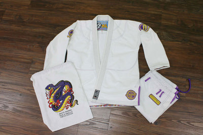 Shoyoroll Batch #8 White Mamba Gi, featuring a lightweight 450 GSM pearl weave jacket and 12 oz ripstop pants. Designed by artist John Smalls, this gi showcases a white base with purple trim. Released as part of the East vs. West Series on December 22, 2010, at 3:00 PM PST.